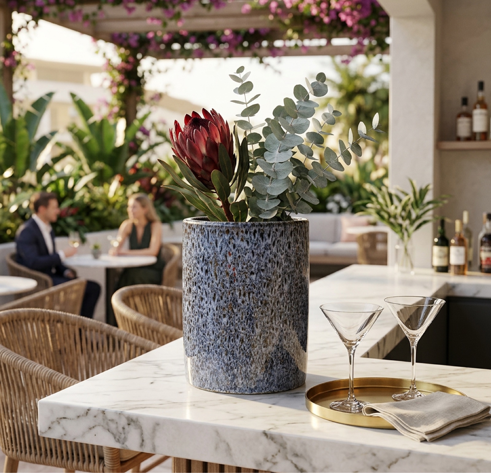 Vaso cilindrico in ceramica screziata blu con ramo di eucalipto su tavolo in marmo