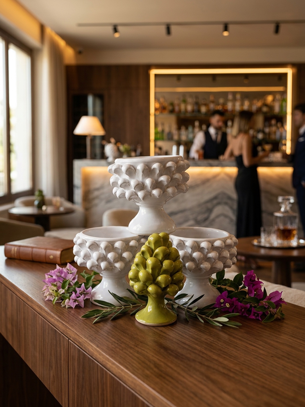 Alzate in ceramica bianca con decoro a pigna e mini pigna verde su bancone di hotel