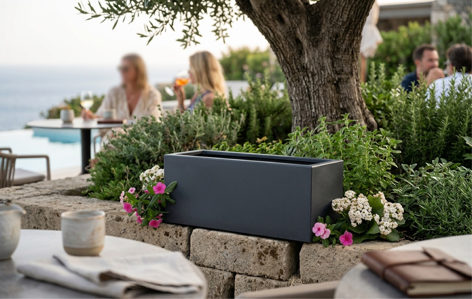 Fioriera rettangolare in resina grigia con piante aromatiche su muretto vista piscina